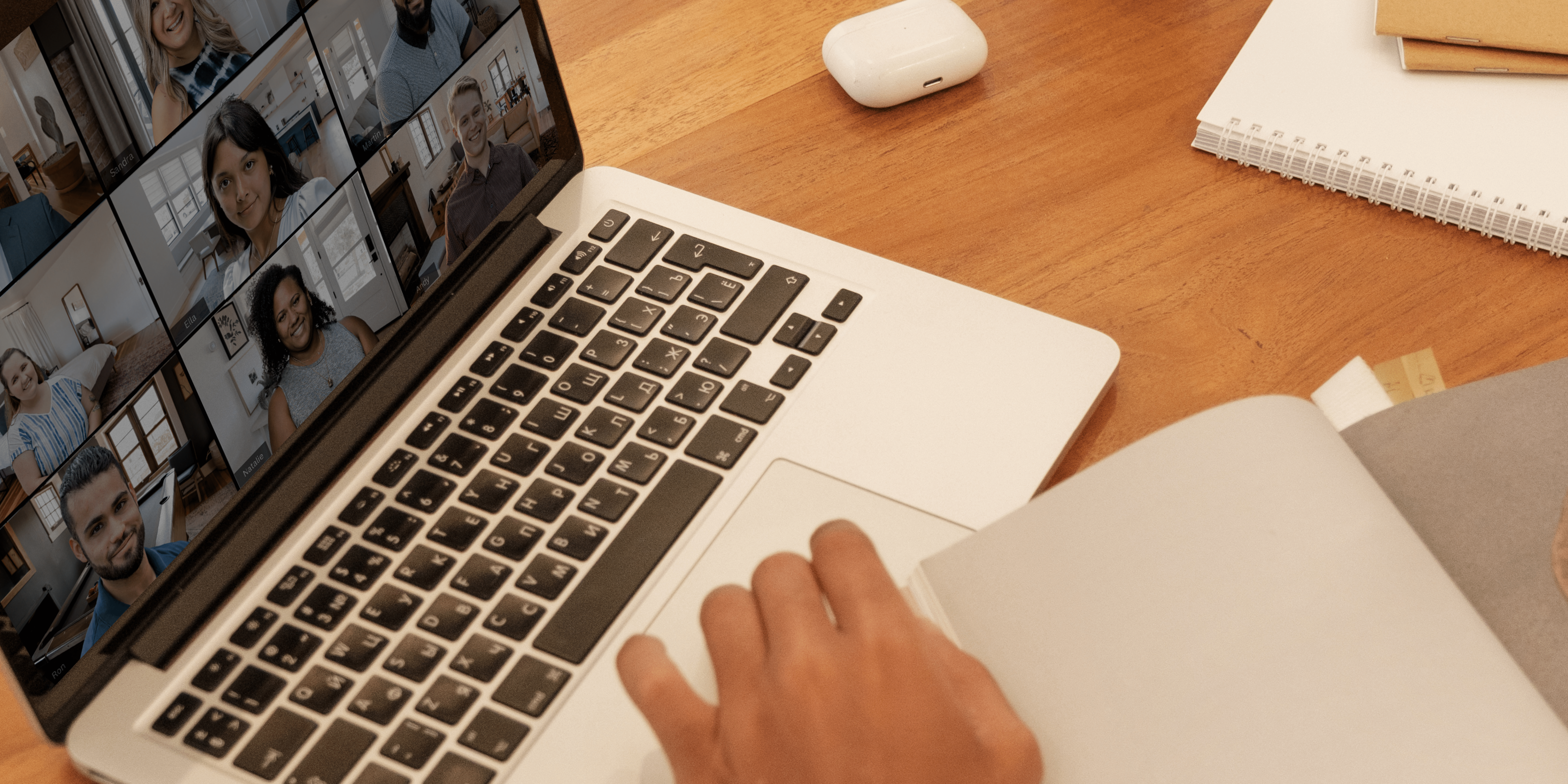 A hand on a laptop that has a webinar on screen